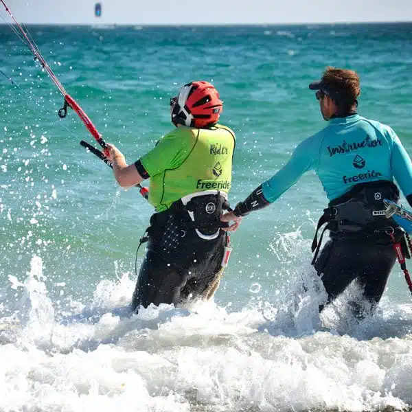 Kitesurf instructor helping his student in the water