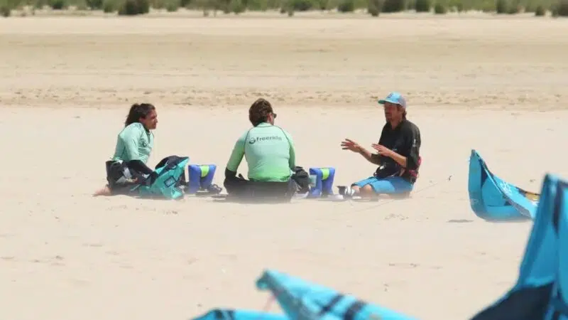 Certified IKO 1 kiteurf course with instructor explaining wind theory and safety to two students on Los Lances beach in Tarifa.