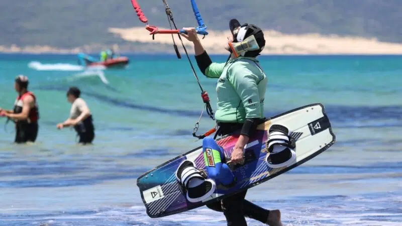 Female beginner kitesurfer standing on the shore at Los Lances beach ready to go to the water in Tarifa