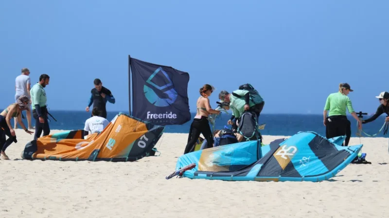 Alumnos de una escuela de kitesurf preparando su material en la playa de Tarifa con instructores profesionales antes de una clase en Cádiz, España.